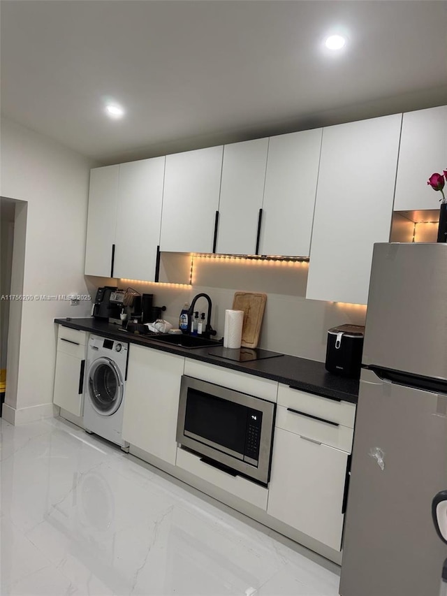 kitchen with stainless steel appliances, washer / clothes dryer, dark countertops, and white cabinets