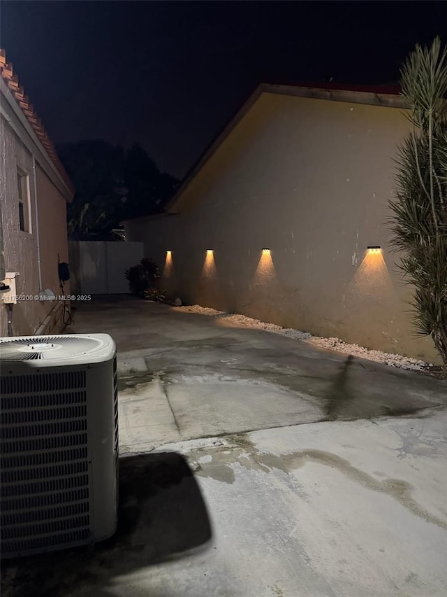 property exterior at night with central AC and a patio