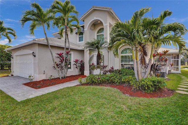 mediterranean / spanish home with a garage, a front lawn, and stucco siding