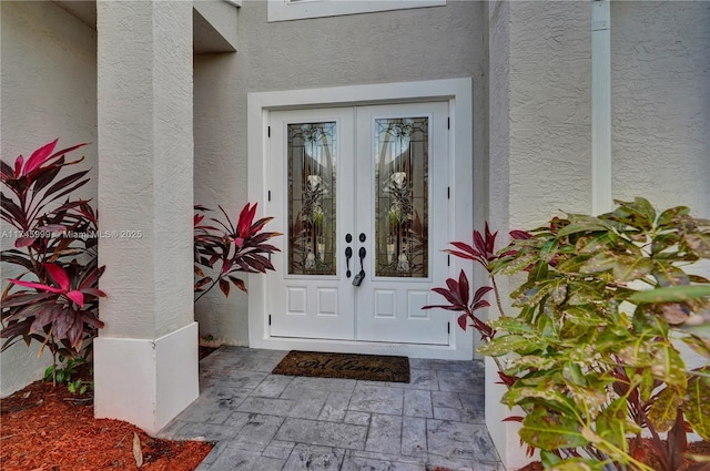 entrance to property featuring french doors and stucco siding