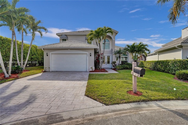 mediterranean / spanish-style home with decorative driveway, french doors, stucco siding, an attached garage, and a front yard