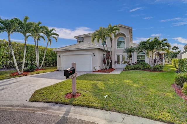 mediterranean / spanish-style house featuring a garage, driveway, french doors, stucco siding, and a front yard