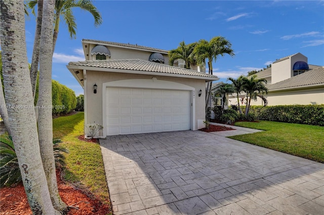 view of front of home featuring decorative driveway, a tiled roof, a front lawn, and stucco siding