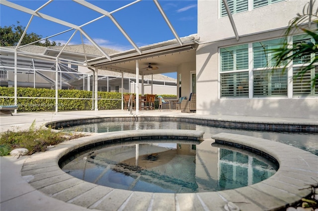 outdoor pool with a ceiling fan, glass enclosure, a patio area, and an in ground hot tub