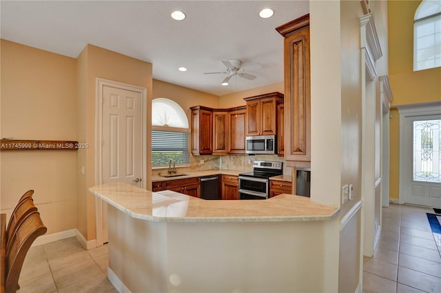 kitchen featuring brown cabinets, light tile patterned floors, stainless steel appliances, and a sink