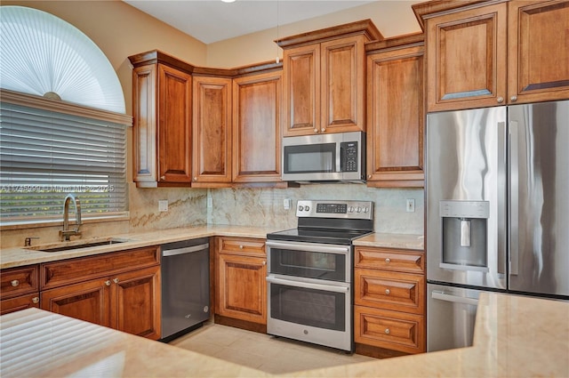 kitchen with brown cabinetry, stainless steel appliances, and a sink