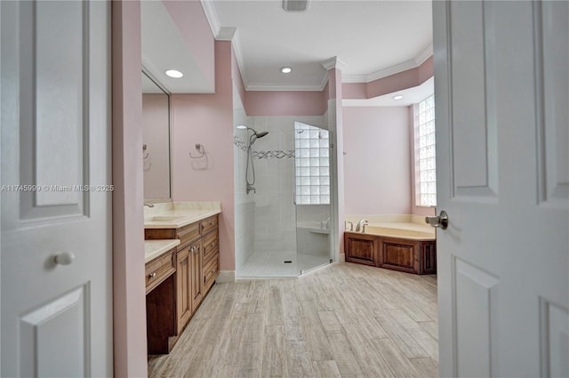bathroom with ornamental molding, a shower stall, vanity, wood finished floors, and a bath