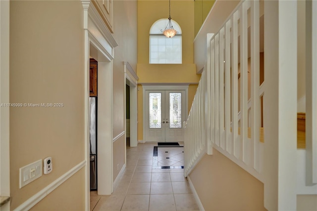 entrance foyer featuring baseboards, a towering ceiling, stairway, french doors, and light tile patterned flooring