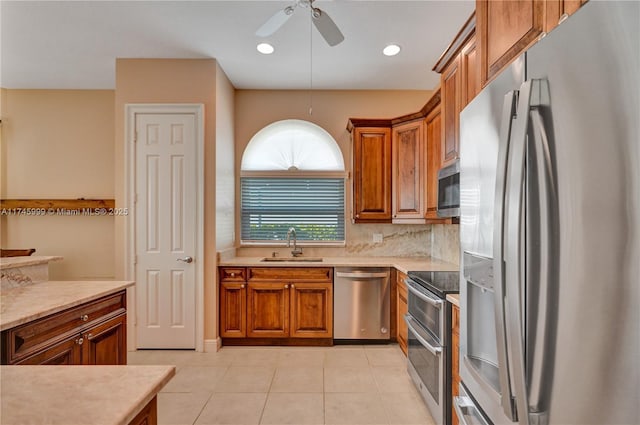 kitchen with stainless steel appliances, light countertops, backsplash, brown cabinetry, and a sink