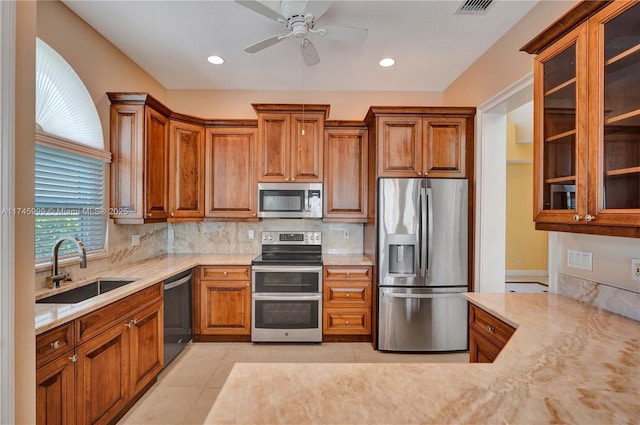 kitchen with decorative backsplash, appliances with stainless steel finishes, brown cabinets, and a sink