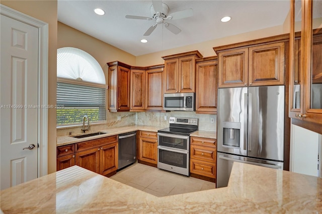 kitchen with stainless steel appliances, light tile patterned flooring, a sink, and brown cabinets