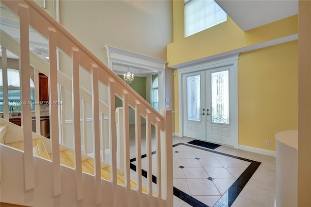 tiled entrance foyer featuring french doors, a high ceiling, plenty of natural light, and baseboards
