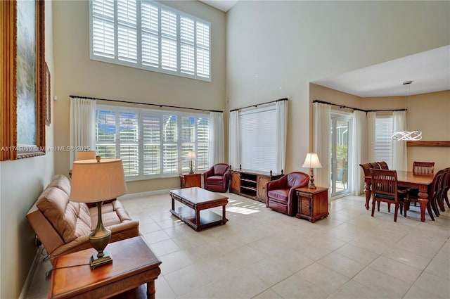 tiled living room with a wealth of natural light, a towering ceiling, and baseboards