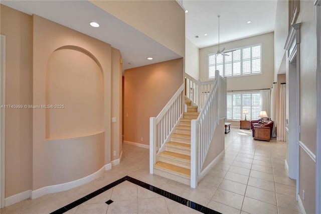 stairs featuring a towering ceiling, tile patterned flooring, baseboards, and recessed lighting