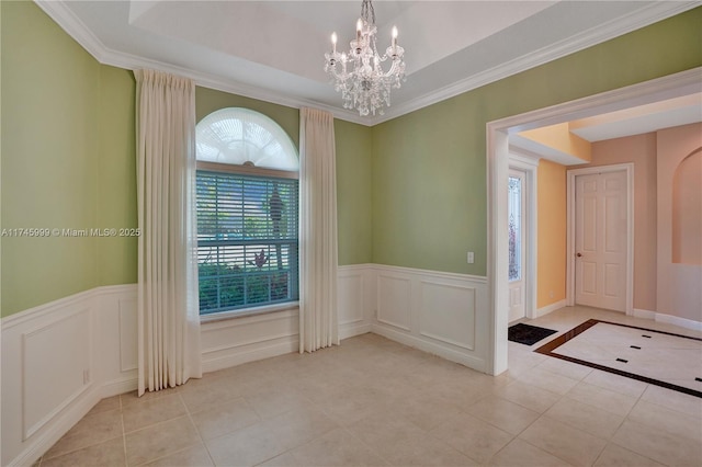 unfurnished room with a wainscoted wall, ornamental molding, a notable chandelier, and light tile patterned flooring