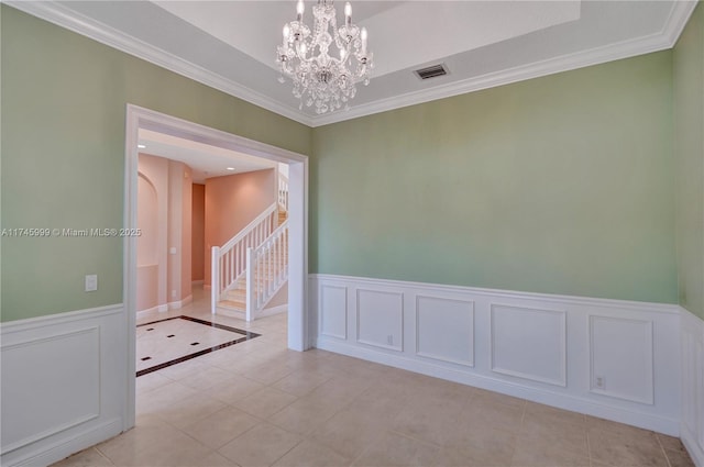 spare room featuring wainscoting, ornamental molding, light tile patterned flooring, and a notable chandelier