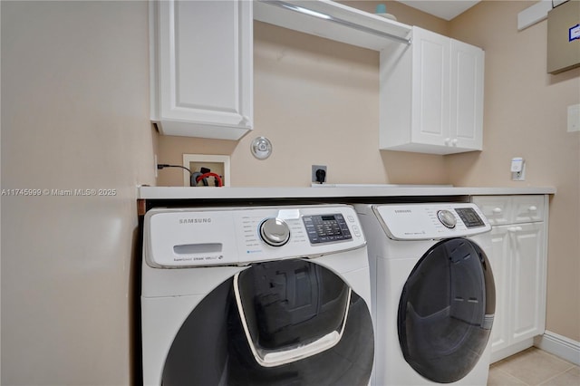 clothes washing area featuring cabinet space, light tile patterned floors, baseboards, and washing machine and clothes dryer
