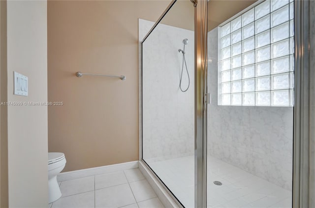 bathroom with baseboards, a stall shower, toilet, and tile patterned floors