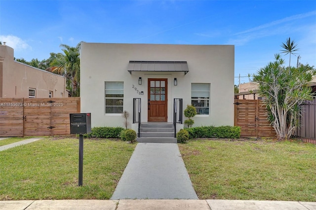 view of front of property featuring a standing seam roof, fence, a front lawn, and metal roof