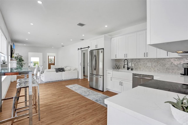 kitchen with white cabinetry, visible vents, stainless steel appliances, and light wood finished floors