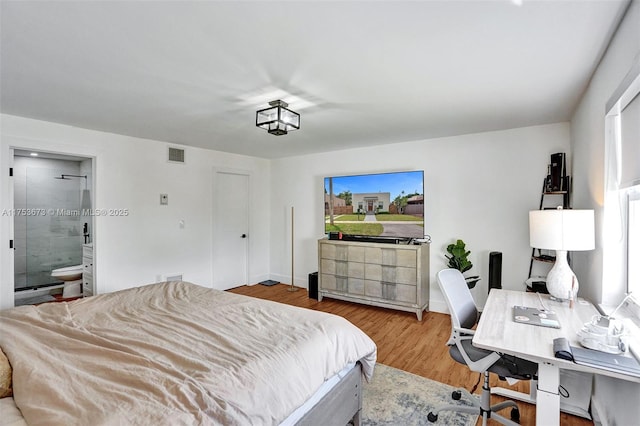 bedroom featuring visible vents, wood finished floors, and ensuite bath