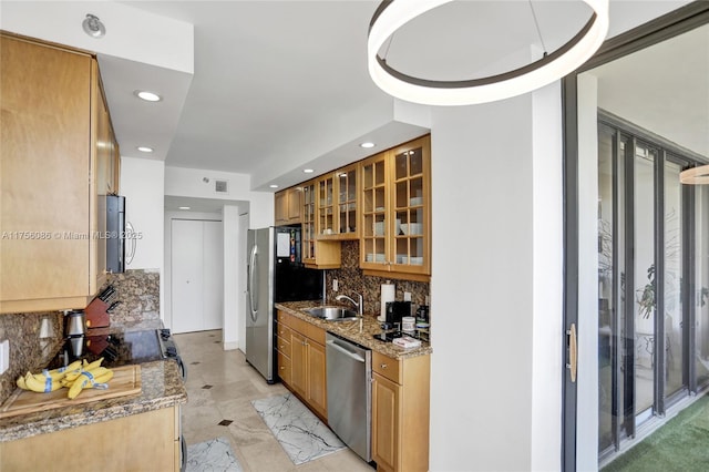 kitchen with tasteful backsplash, brown cabinetry, glass insert cabinets, appliances with stainless steel finishes, and a sink