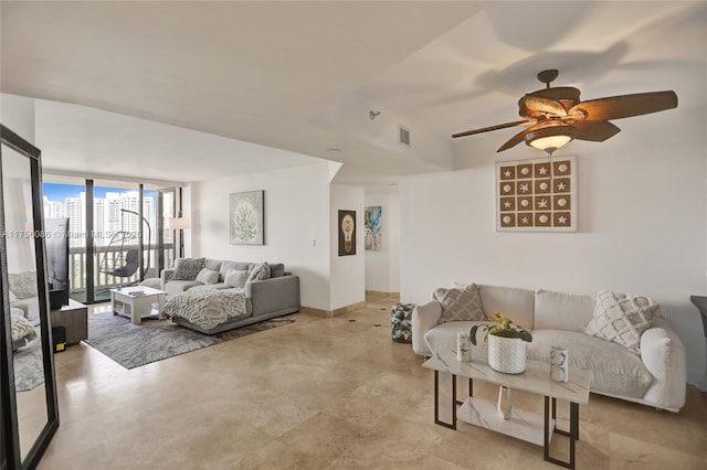 living room featuring a ceiling fan, expansive windows, visible vents, and baseboards