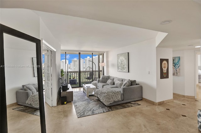 living room featuring baseboards, a wall of windows, and a city view