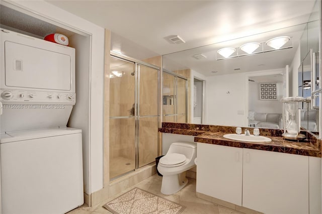 bathroom featuring a stall shower, toilet, vanity, and stacked washing maching and dryer