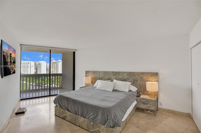 bedroom with access to exterior, a view of city, baseboards, and a wall of windows