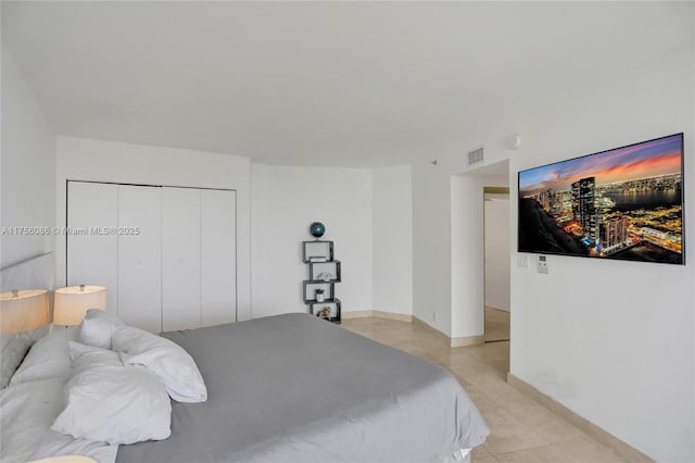 bedroom with light tile patterned floors, baseboards, visible vents, and a closet