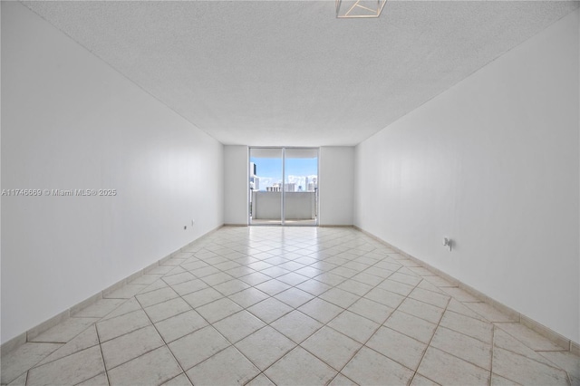 empty room with light tile patterned floors, visible vents, expansive windows, a city view, and a textured ceiling