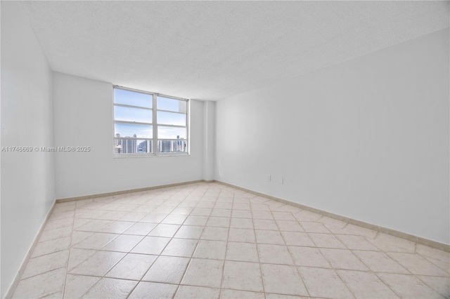 empty room featuring a textured ceiling and baseboards