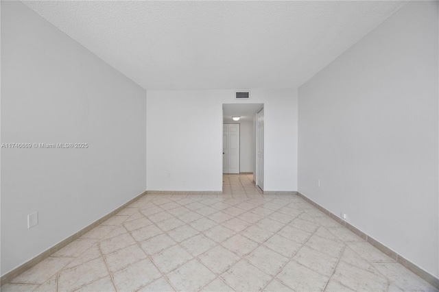 spare room with light floors, baseboards, visible vents, and a textured ceiling