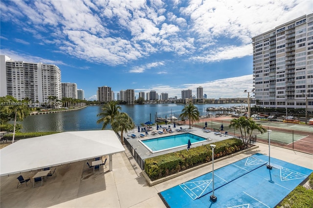 view of swimming pool with a water view, shuffleboard, and a city view