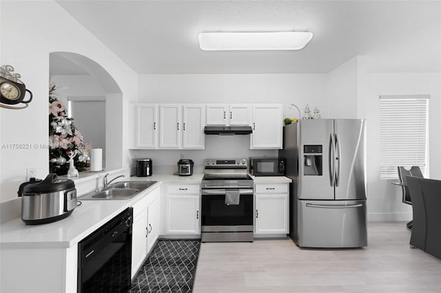 kitchen featuring black appliances, under cabinet range hood, white cabinets, and a sink