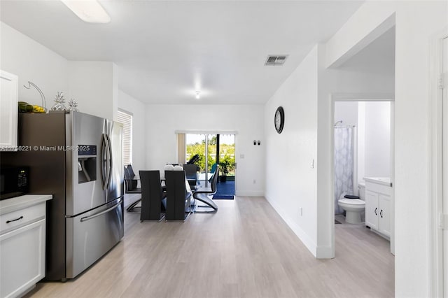 kitchen featuring visible vents, white cabinetry, light wood-type flooring, black microwave, and stainless steel fridge with ice dispenser