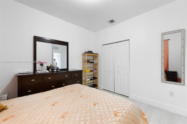 bedroom featuring a closet, visible vents, baseboards, and wood finished floors