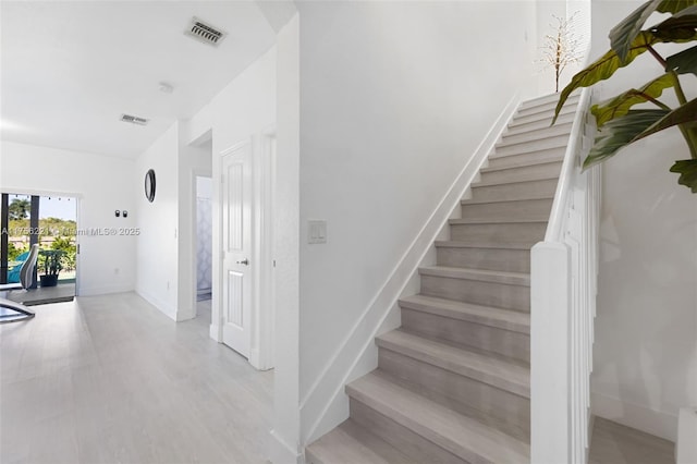 stairway featuring visible vents, baseboards, and wood finished floors