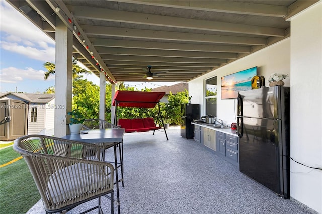 view of patio with an outbuilding, ceiling fan, a sink, a shed, and outdoor dining space