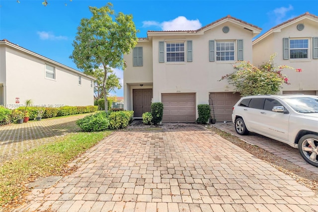 view of front of property featuring a garage, a tiled roof, decorative driveway, and stucco siding