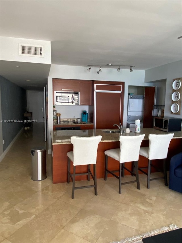 kitchen featuring a breakfast bar, visible vents, refrigerator, and stainless steel microwave