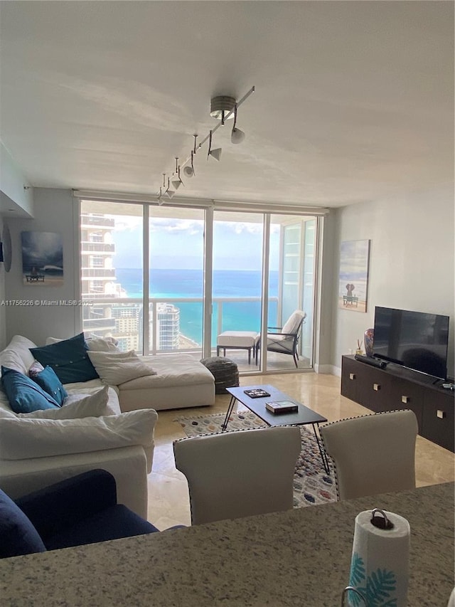 living room featuring rail lighting, plenty of natural light, and floor to ceiling windows