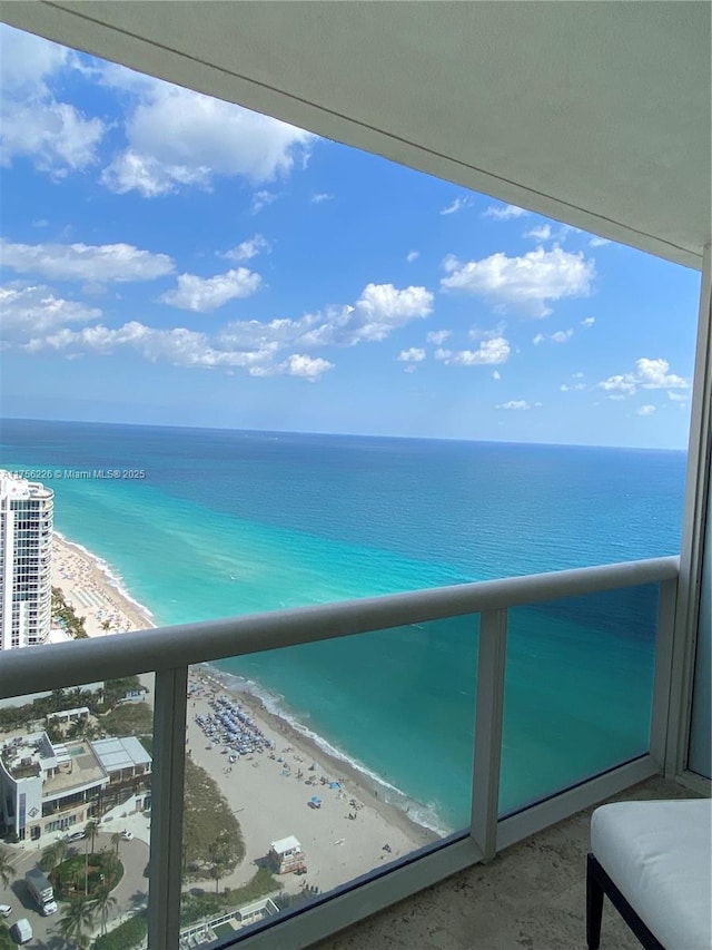 balcony featuring a view of the beach and a water view