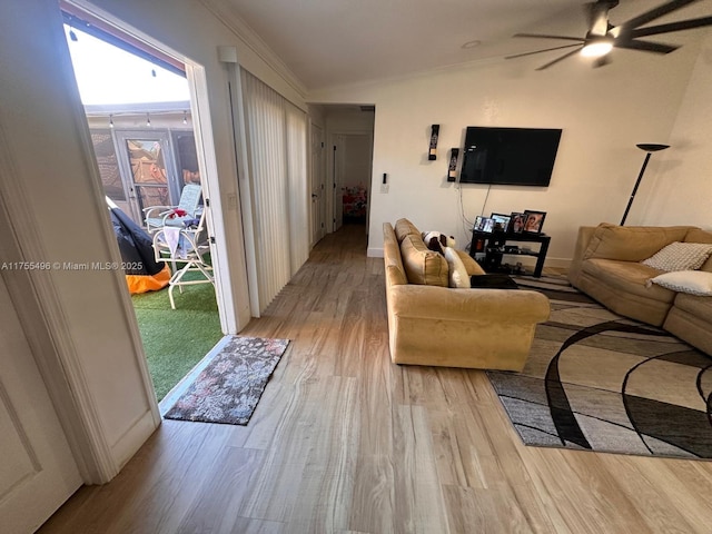 living room with baseboards, a ceiling fan, light wood-style flooring, and crown molding