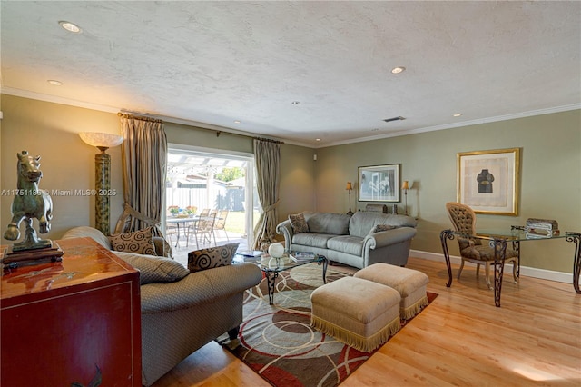 living room with visible vents, baseboards, ornamental molding, light wood-style flooring, and a textured ceiling