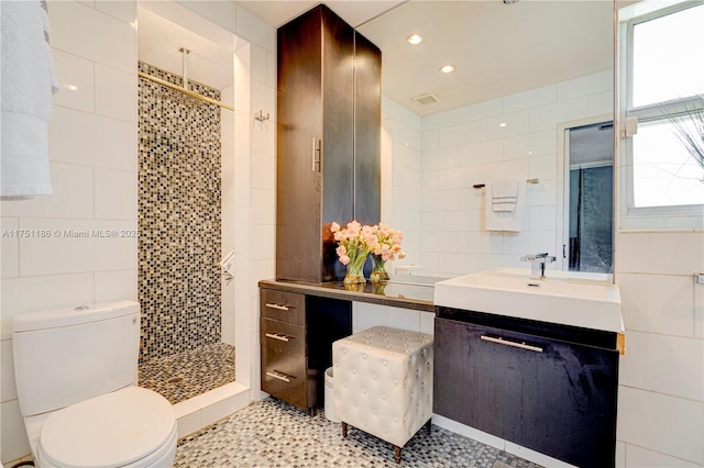 full bath with vanity, tiled shower, recessed lighting, tile walls, and toilet