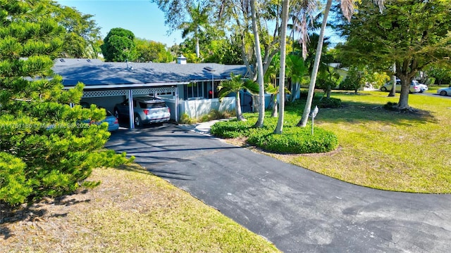 view of front of home featuring a carport, driveway, a shingled roof, and a front lawn