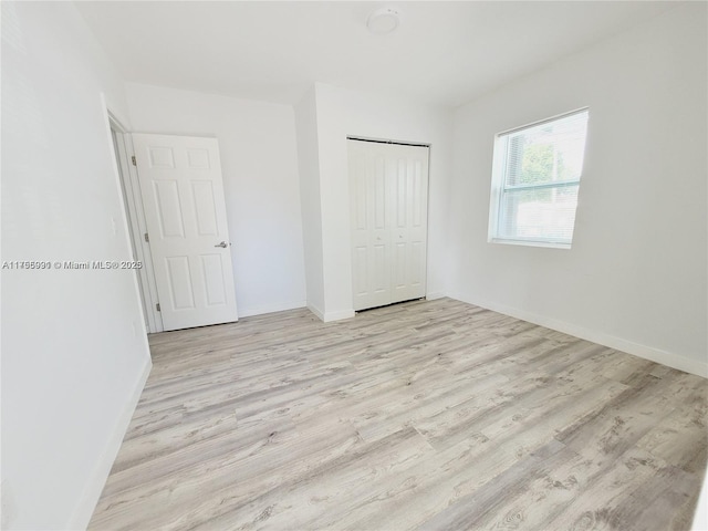 unfurnished bedroom featuring a closet, light wood-style flooring, and baseboards