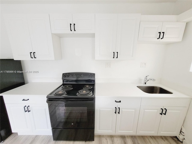 kitchen with light countertops, white cabinetry, a sink, and electric range